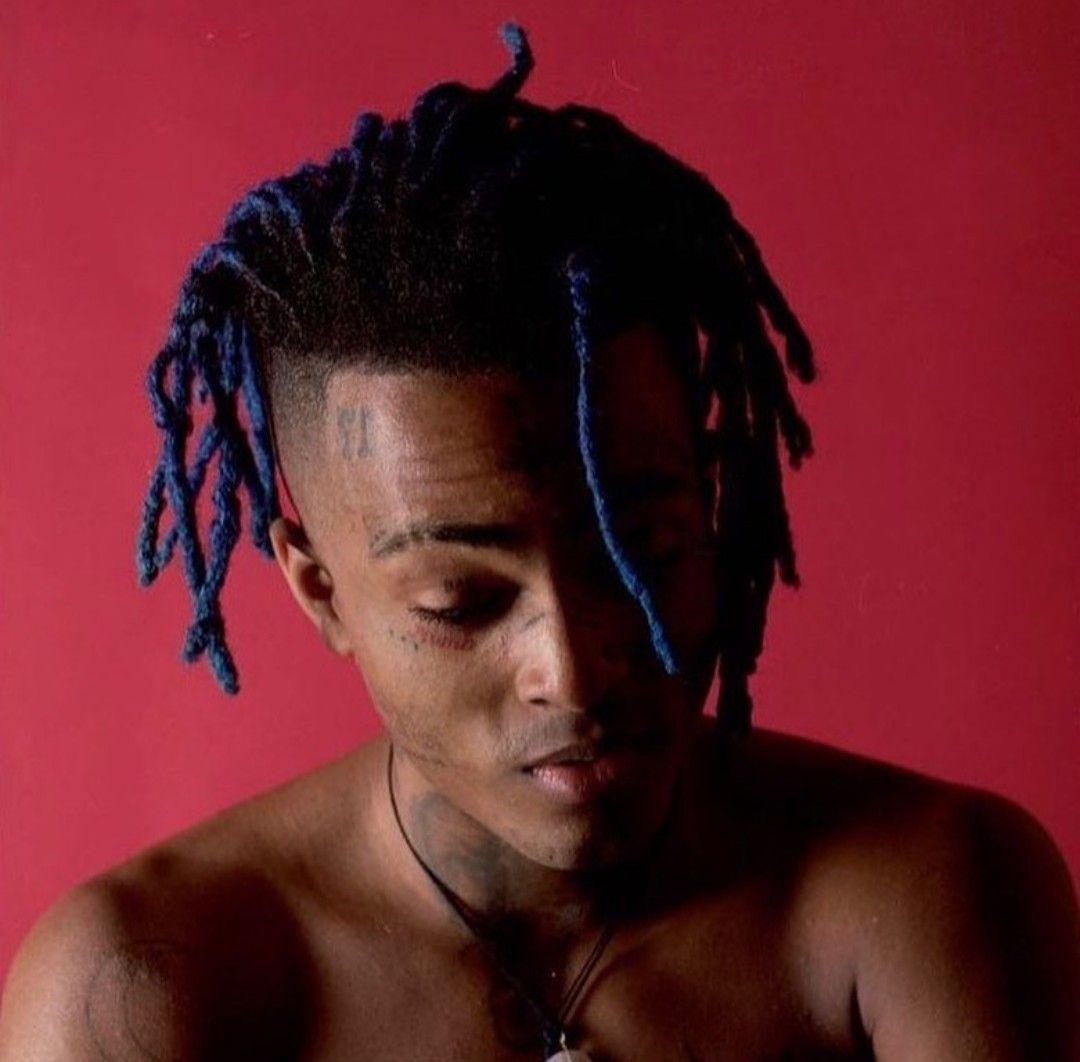 XXXTENTACION with blue hair against a red background